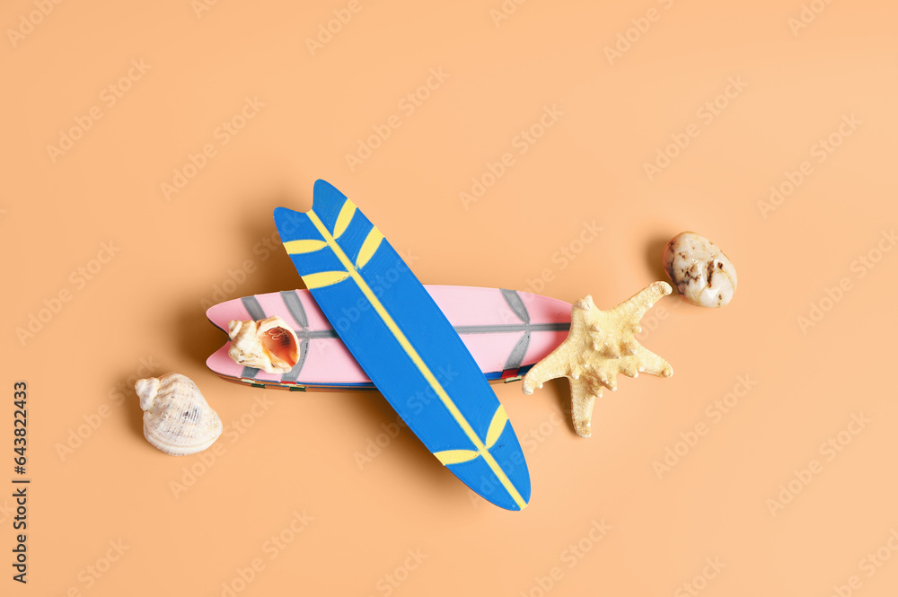 Different mini surfboards, stone, seashells and starfish on orange background