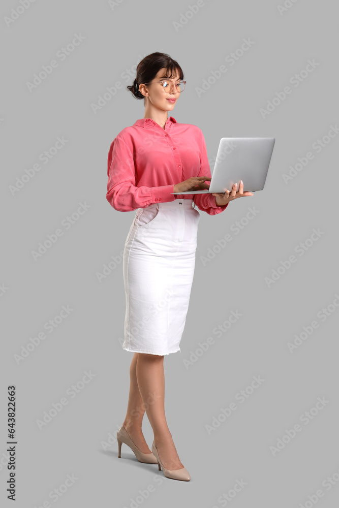 Beautiful businesswoman working with laptop on grey background