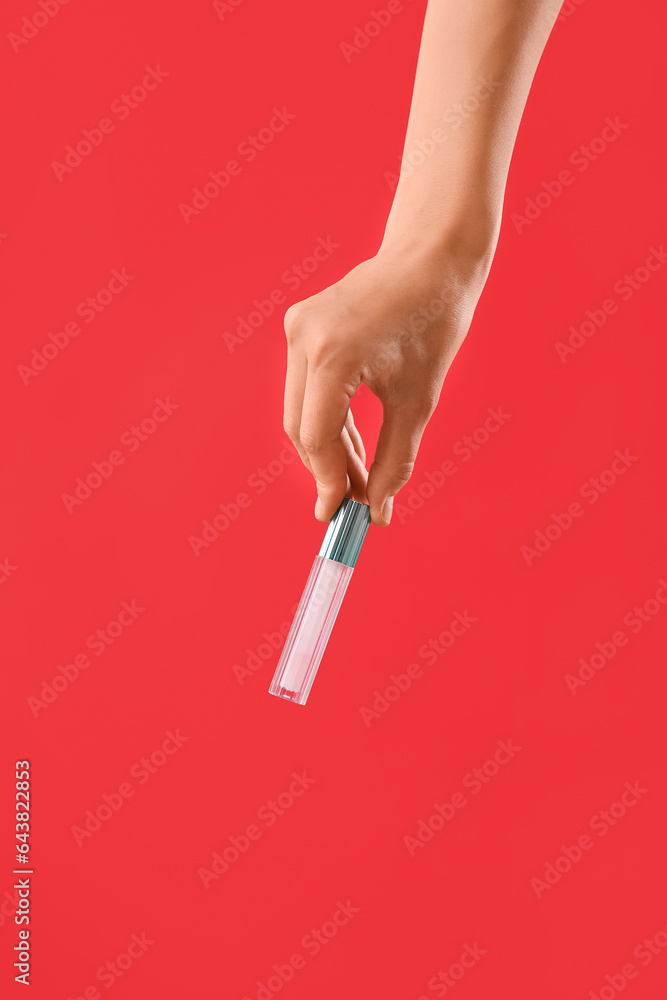 Woman with lip gloss on red background