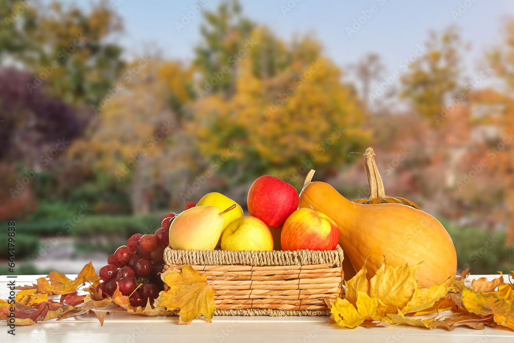 Basket with different vegetables and fruits on table outdoors. Harvest festival