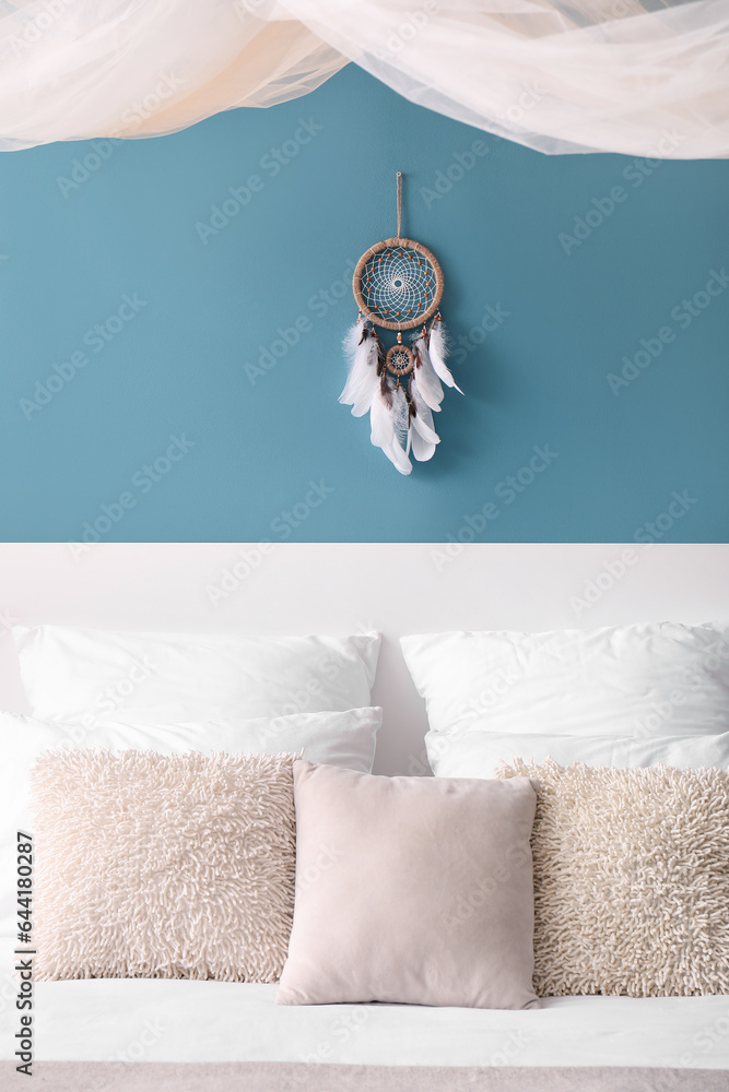 Dream catcher hanging on blue wall in bedroom