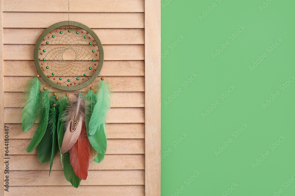 Folding screen with dream catcher near green wall, closeup