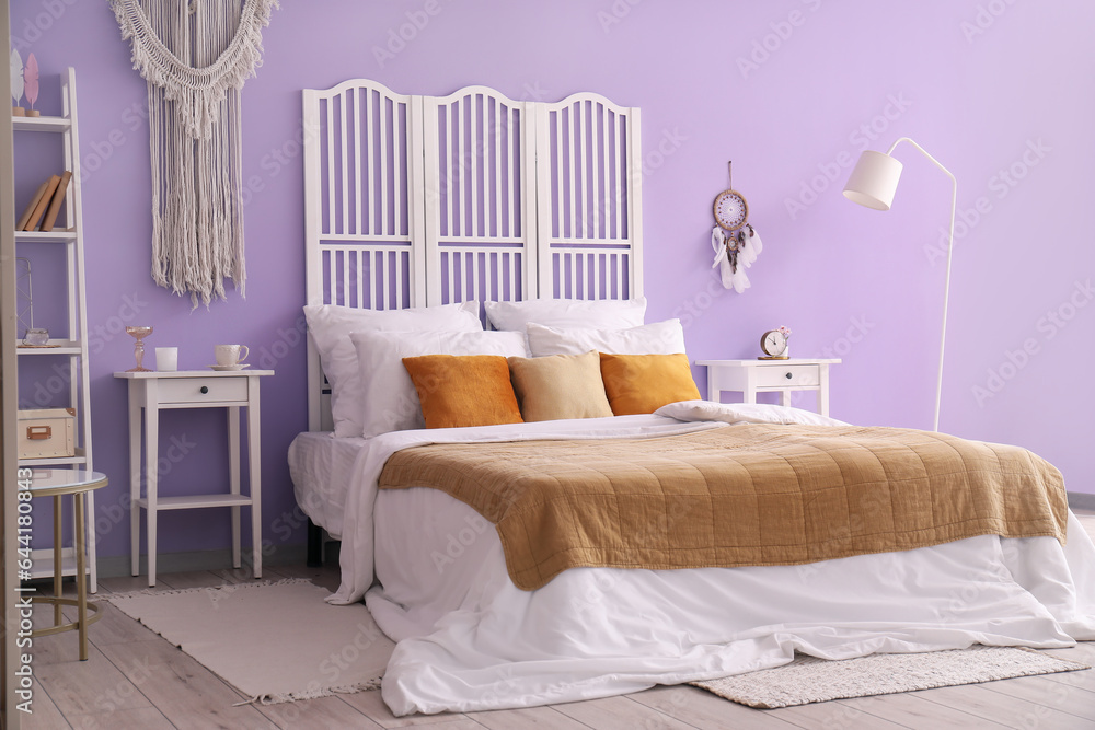 Interior of stylish bedroom with dream catcher, bed and folding screen