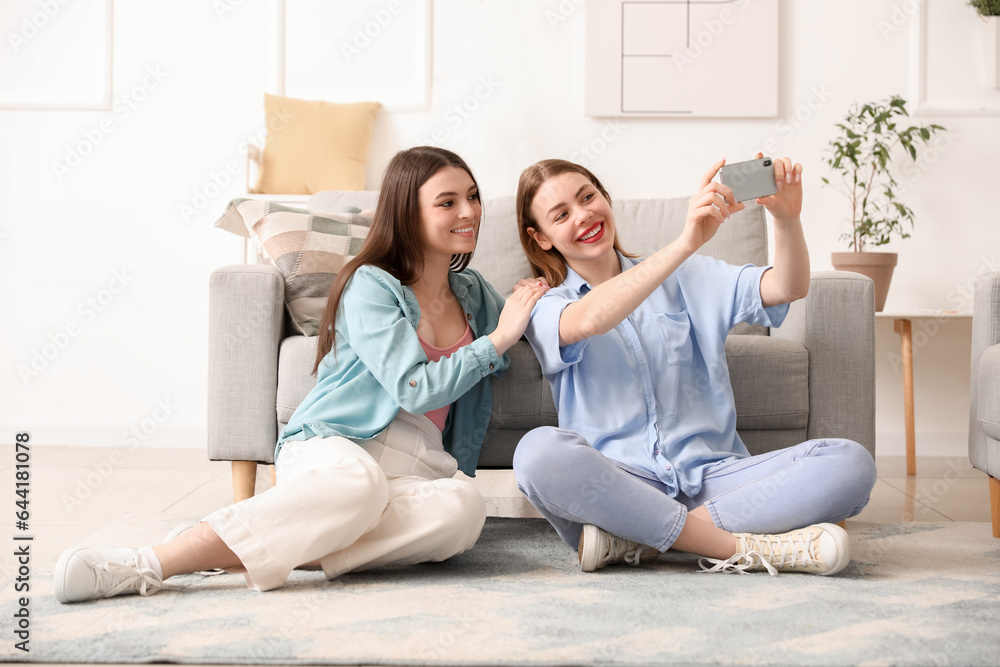 Female friends with mobile phone taking selfie at home