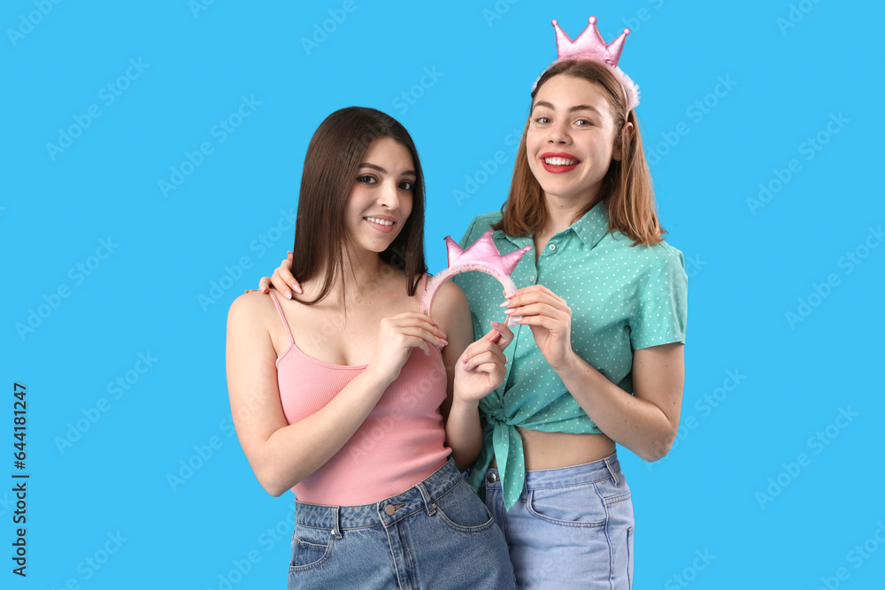 Female friends with crowns on blue background