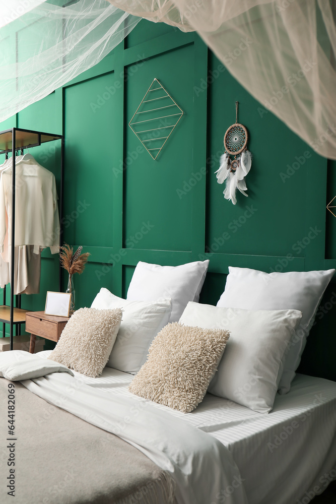 Interior of stylish bedroom with curtain and dream catcher on green wall