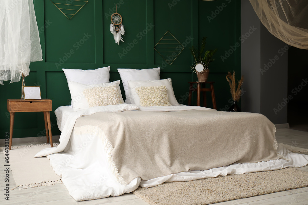 Interior of stylish bedroom with dream catcher on green wall