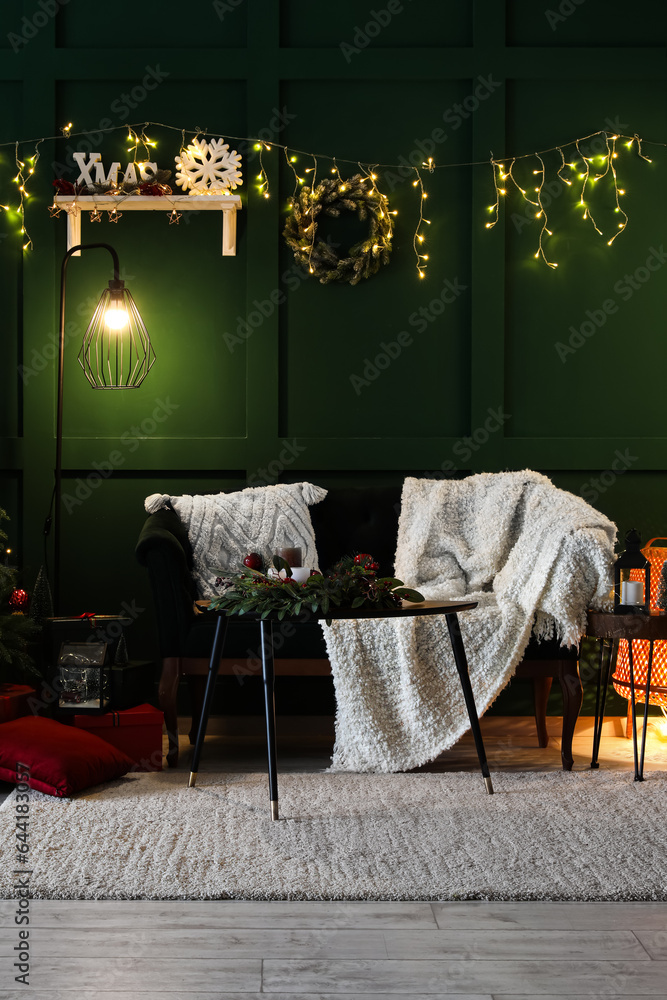 Interior of living room decorated for Christmas with glowing lights, wreath and sofa