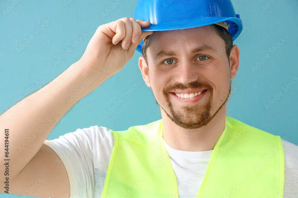 Male builder in hardhat on blue background, closeup