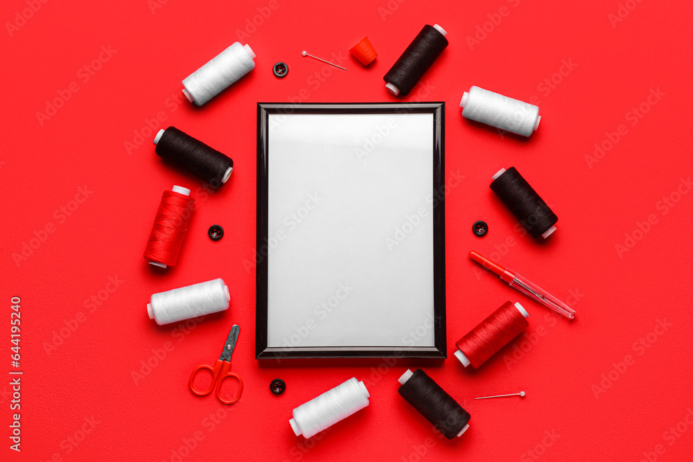 Blank picture frame with sewing supplies on red background