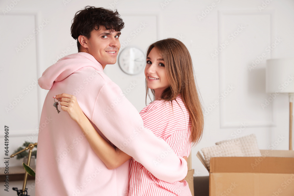 Young couple with keys hugging in their new flat