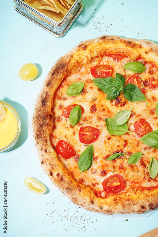 Tasty pizza Margarita with tomatoes and basil on blue table