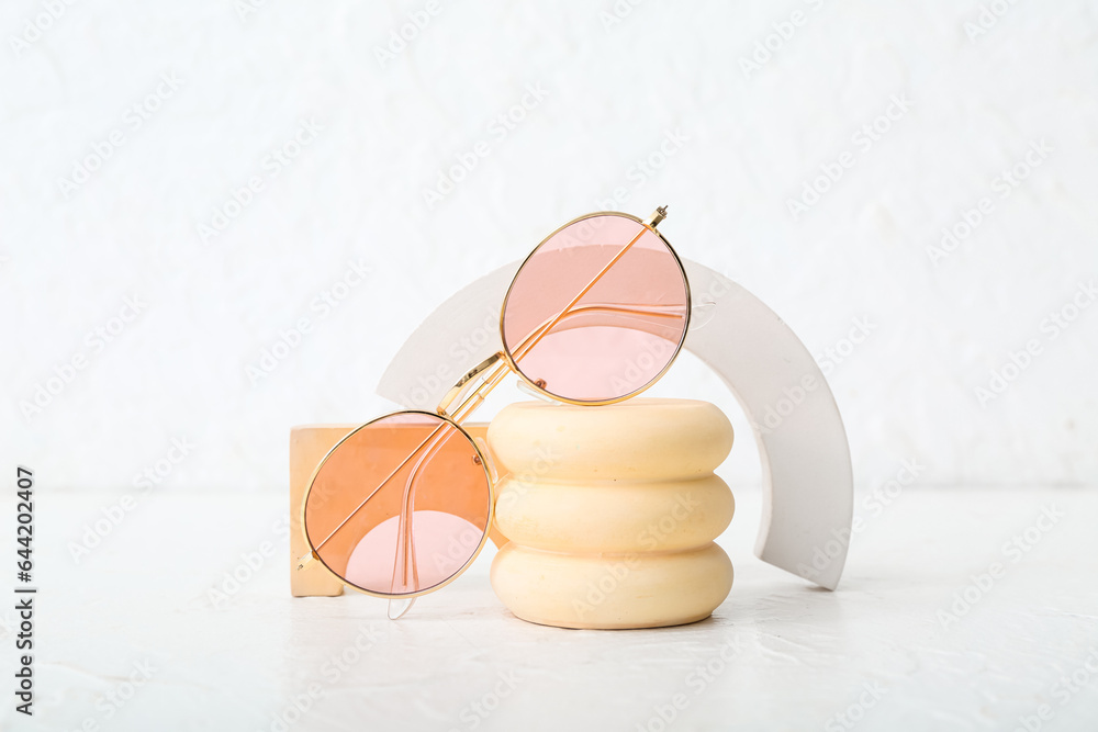 Decorative podiums with stylish sunglasses on white background