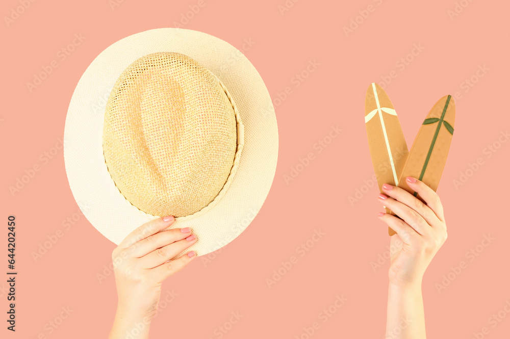 Female hands with mini surfboards and wicker hat on red background