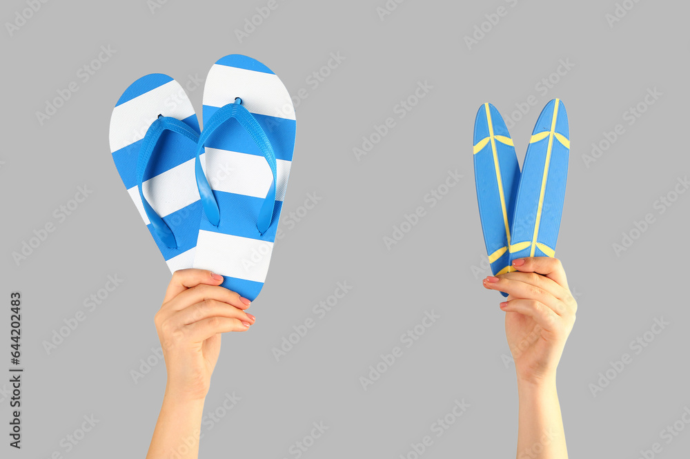 Female hands with mini surfboards and flip flops on grey background