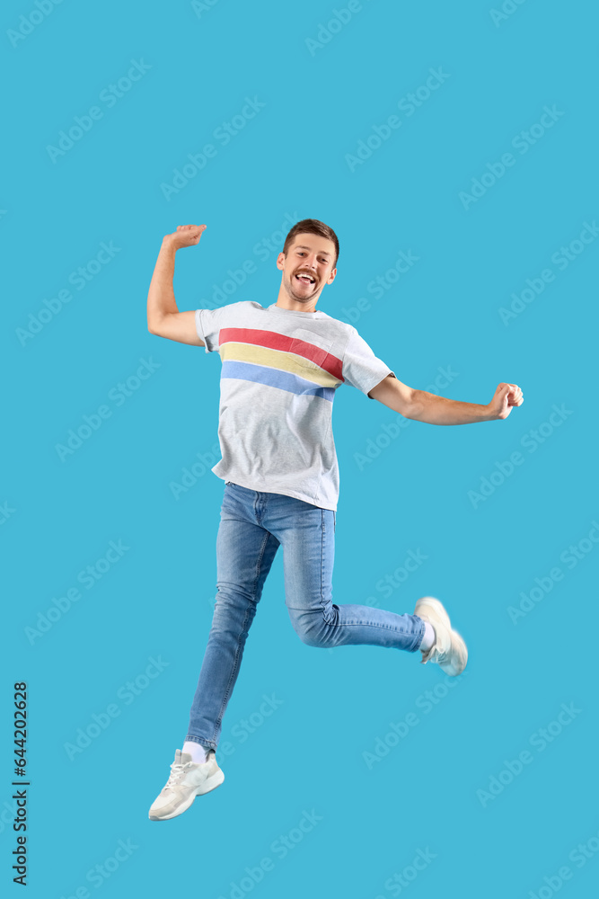 Happy jumping young man on blue background