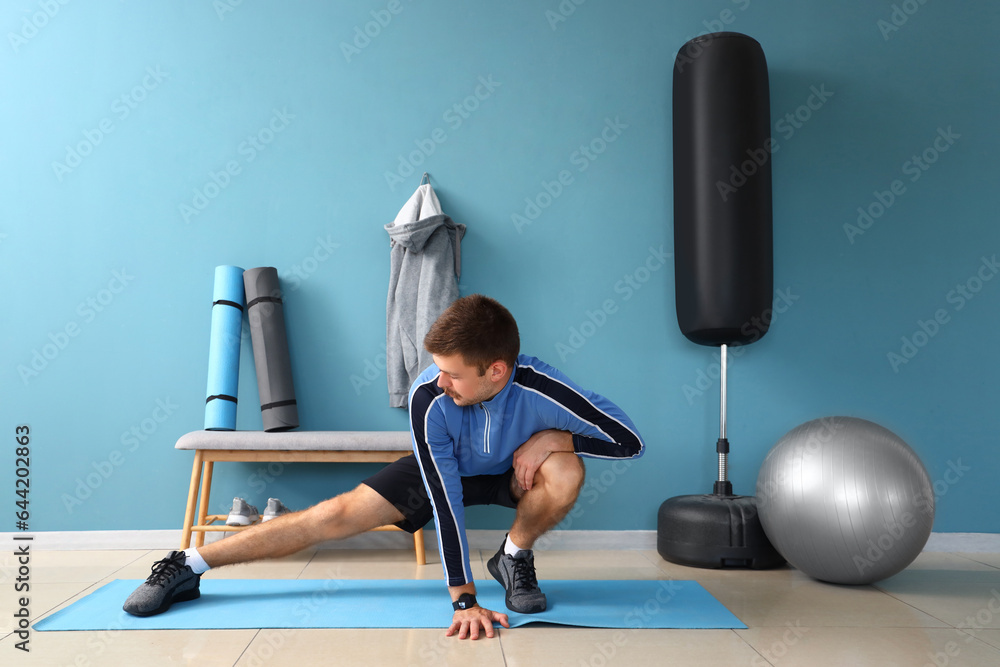 Sporty young man stretching in gym