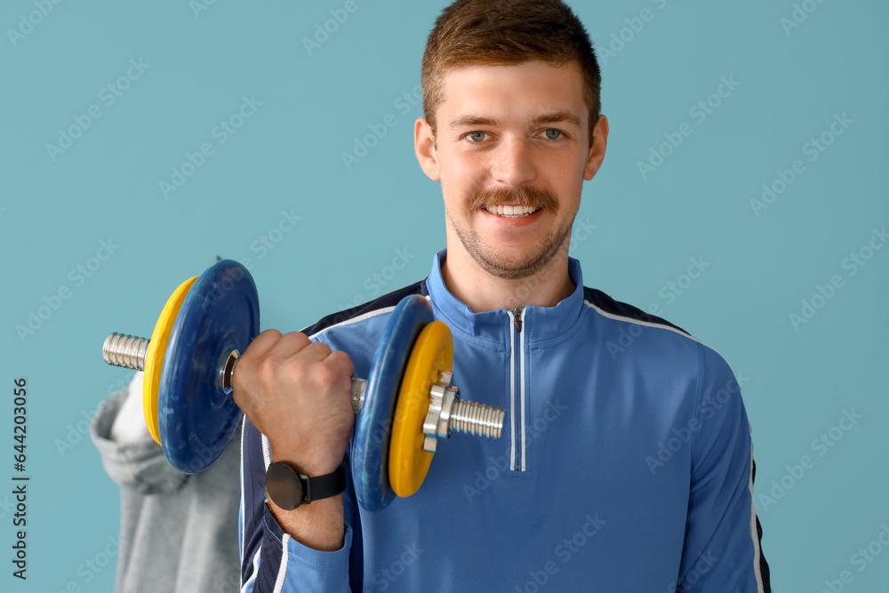 Sporty young man doing exercise with dumbbells in gym