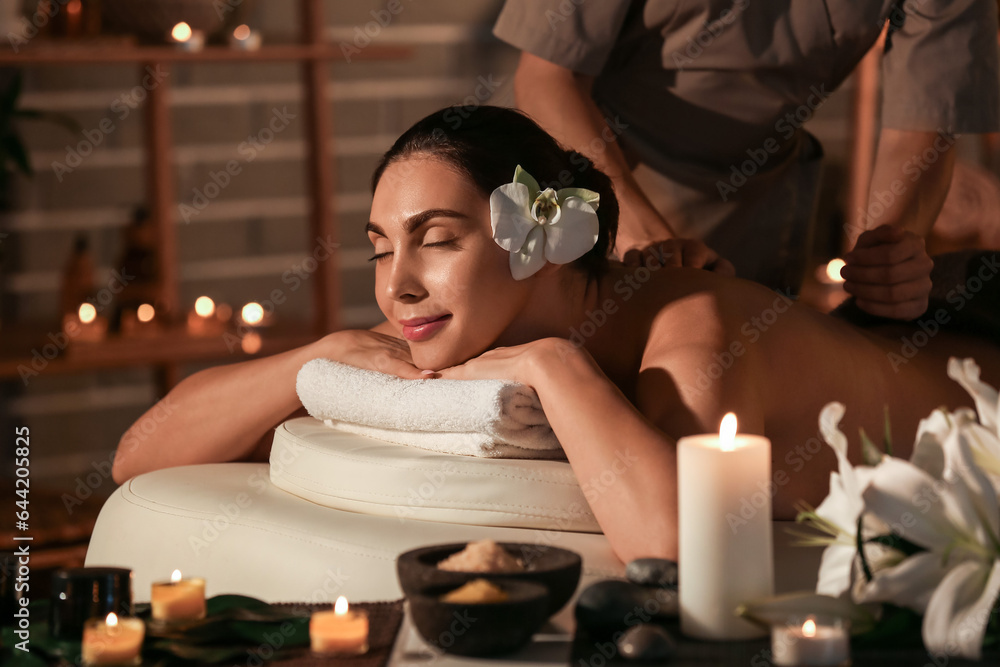 Young woman getting massage in dark spa salon, closeup