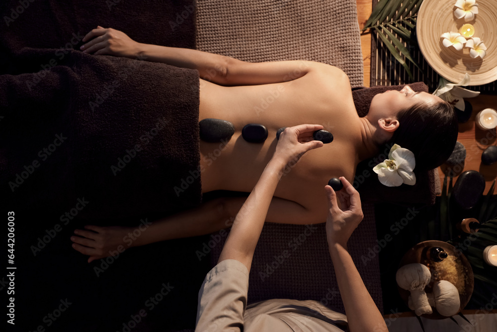 Young woman undergoing treatment with stones in dark spa salon, top view