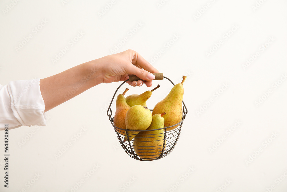 Woman holding basket with ripe pears on white background