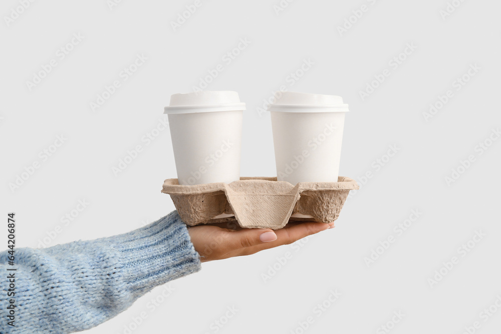 Woman with takeaway cups of tasty coffee on white background