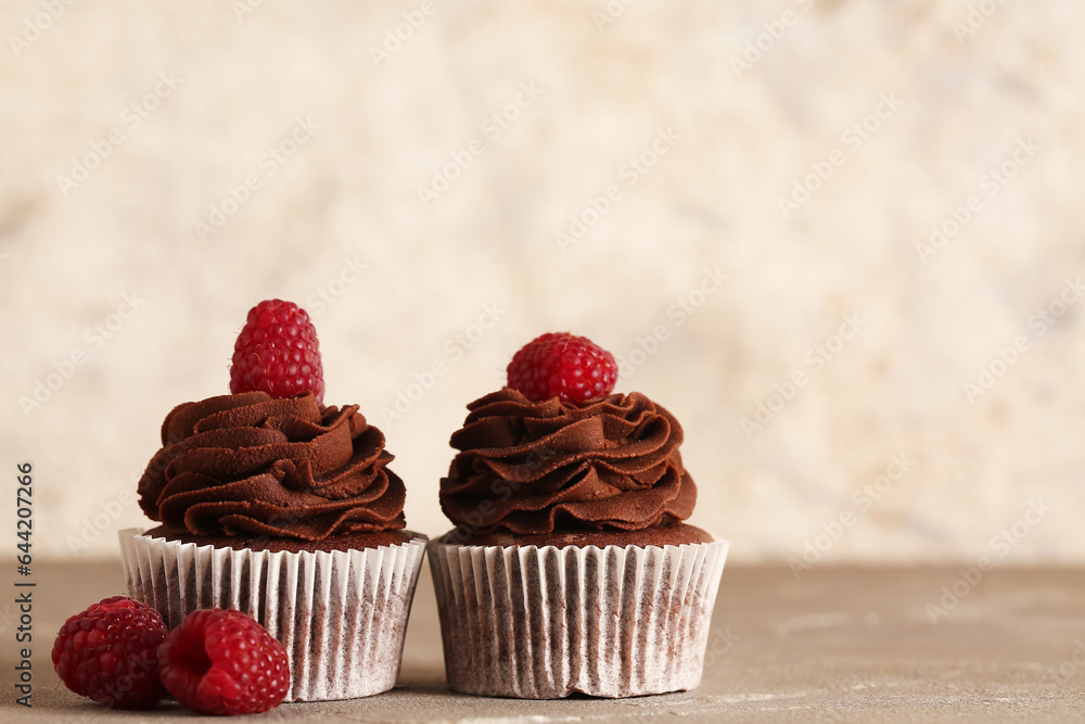 Tasty chocolate cupcakes with raspberry on table