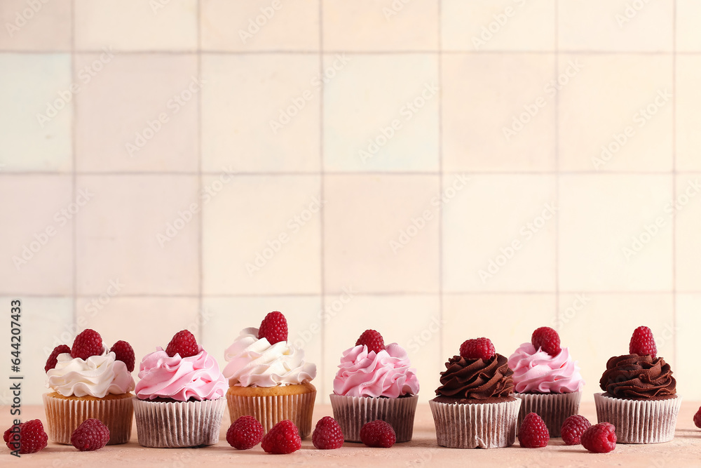 Tasty cupcakes with raspberries on table