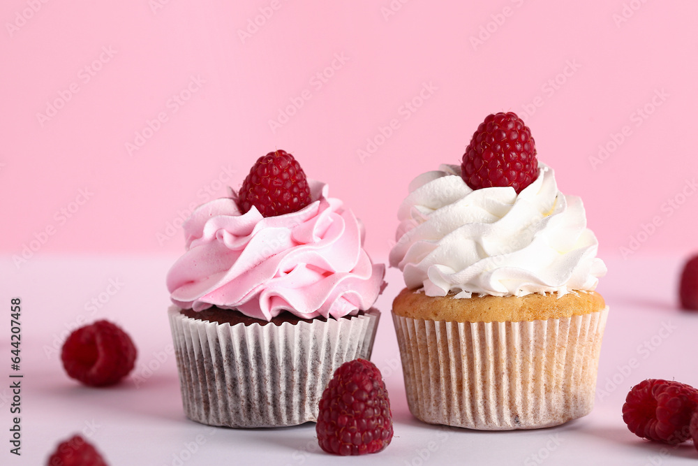 Tasty raspberry cupcakes and fresh berries on pink background