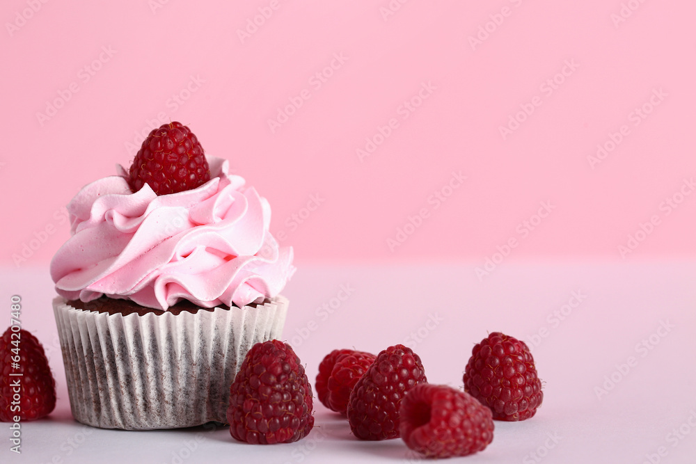 Tasty raspberry cupcakes and fresh berries on pink background