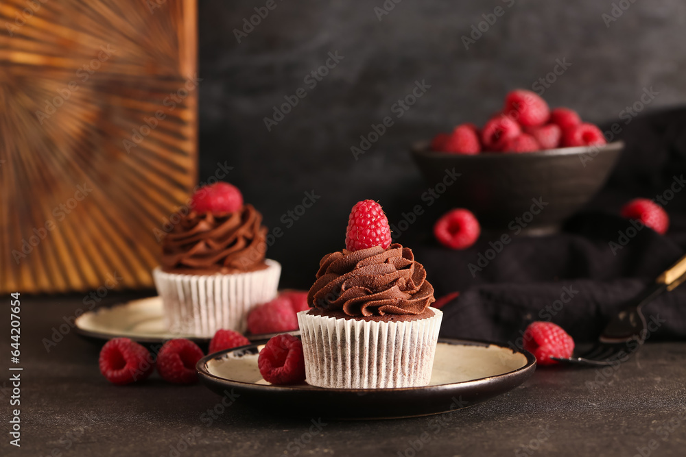 Plate of tasty chocolate cupcake with raspberries on black background