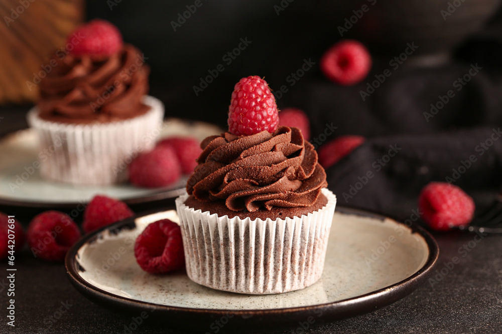 Plate of tasty chocolate cupcake with raspberries on black background