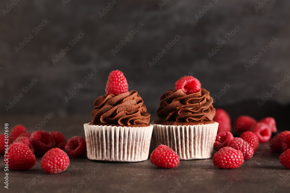 Tasty chocolate cupcakes with raspberries on black background