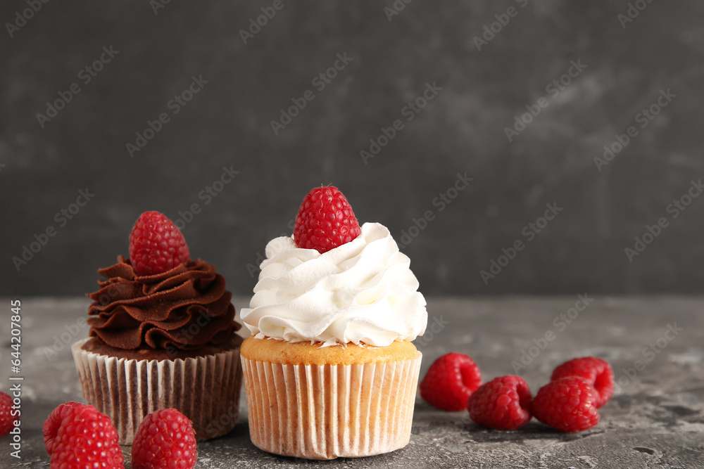 Tasty cupcakes with raspberries on table