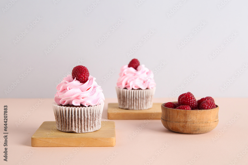 Tasty raspberry cupcakes and fresh berries on beige background