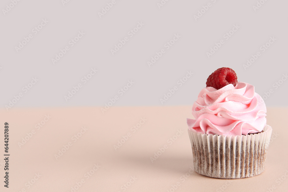 Tasty raspberry cupcake on beige background