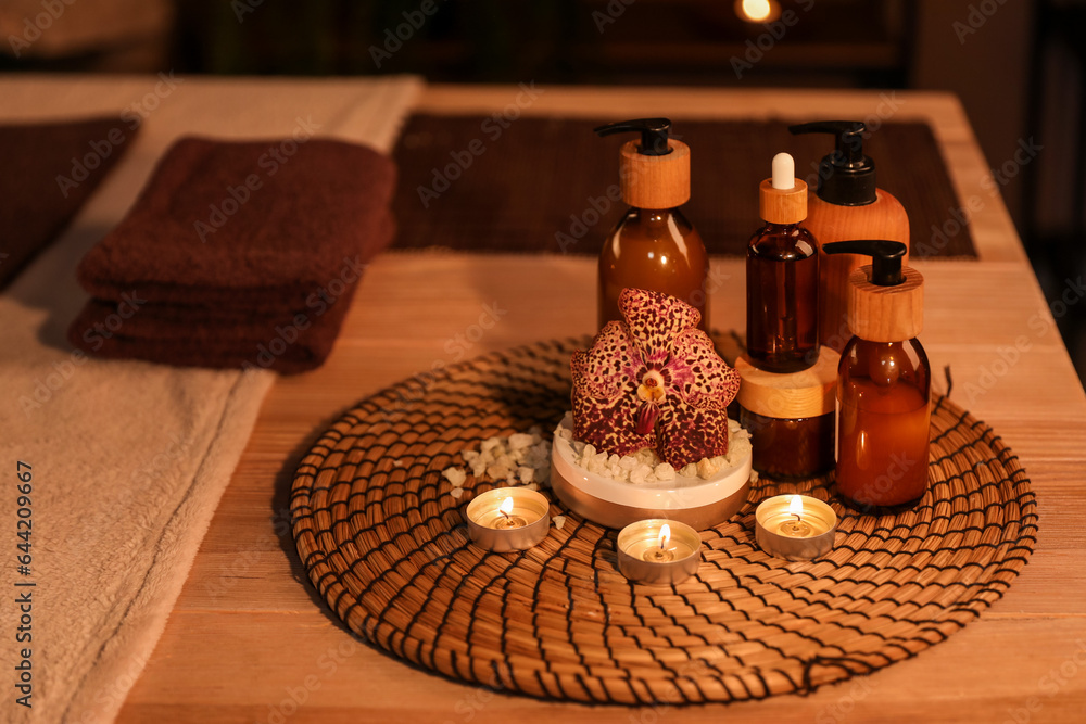 Spa composition with burning candles on table in dark salon, closeup