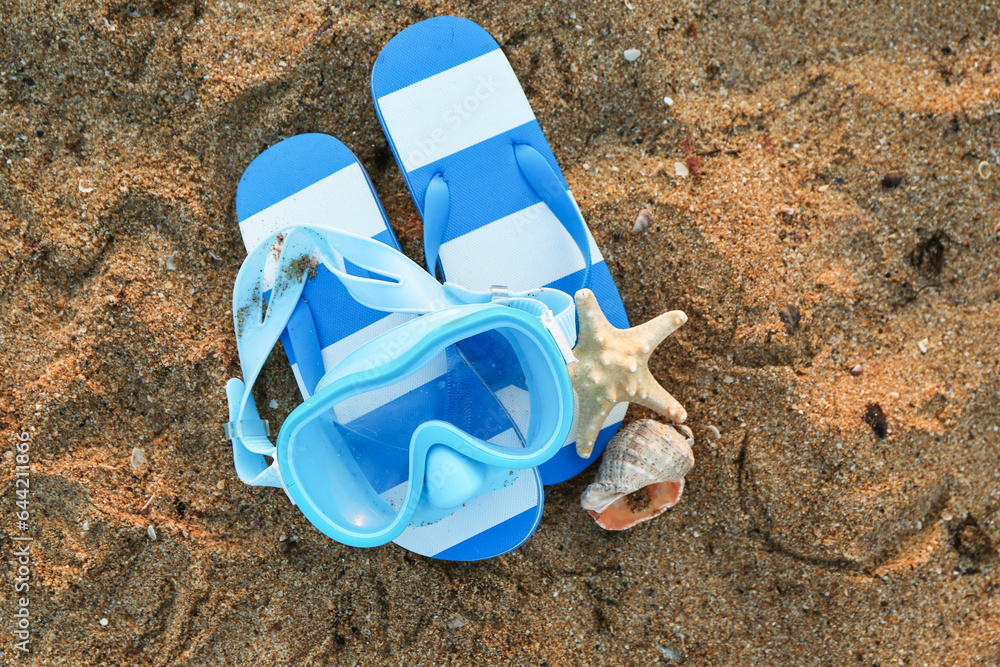 New swimming mask, flip-flops, seashell and starfish on sand