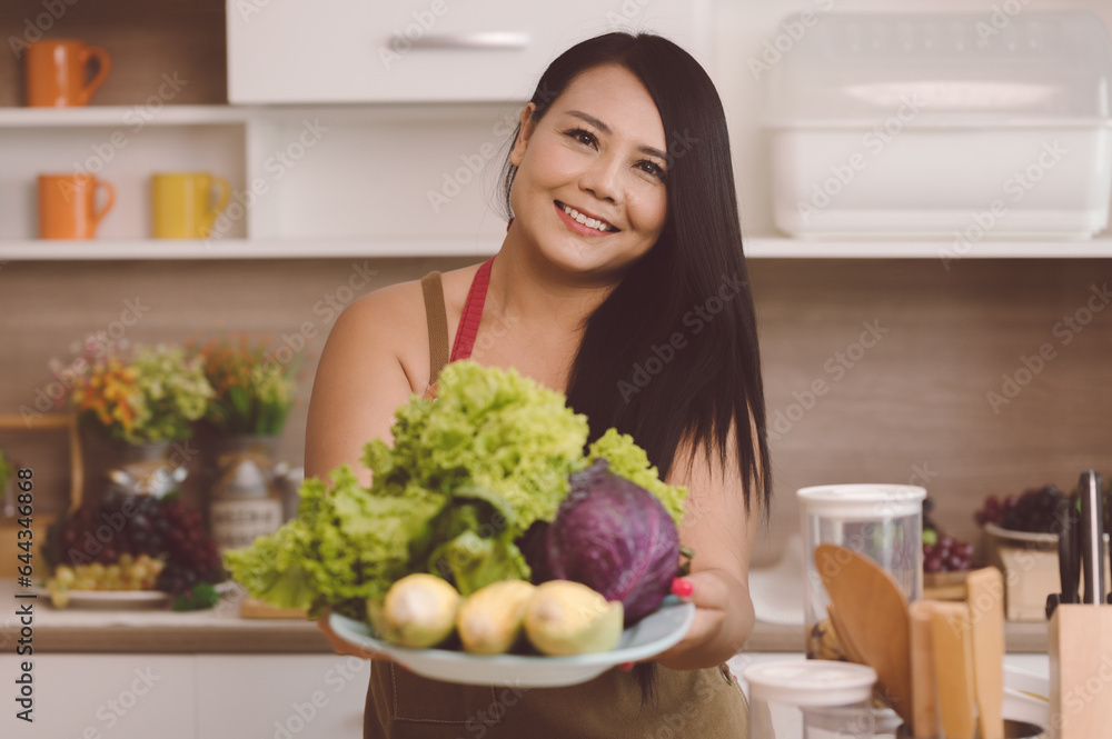 Cheerful fat beautiful Asian woman standing happily smiling at the kitchen counter preparing to mix 