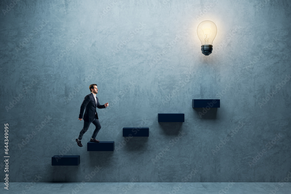 Side view of young businessman climbing illuminated light bulb stairs to success on concrete wall ba