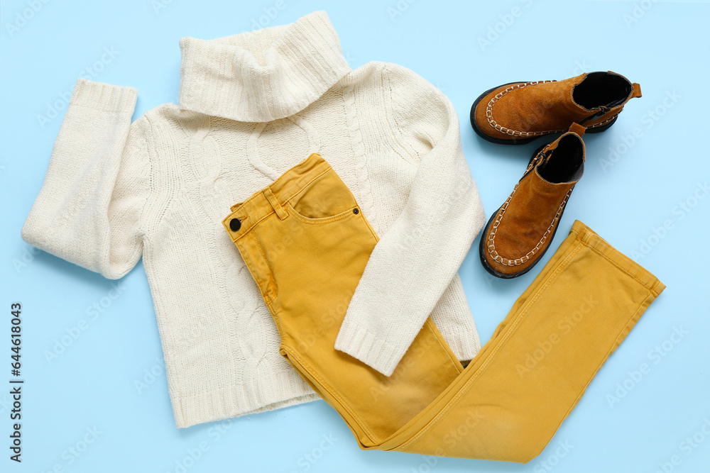 Stylish childrens sweater, pants and shoes on color background