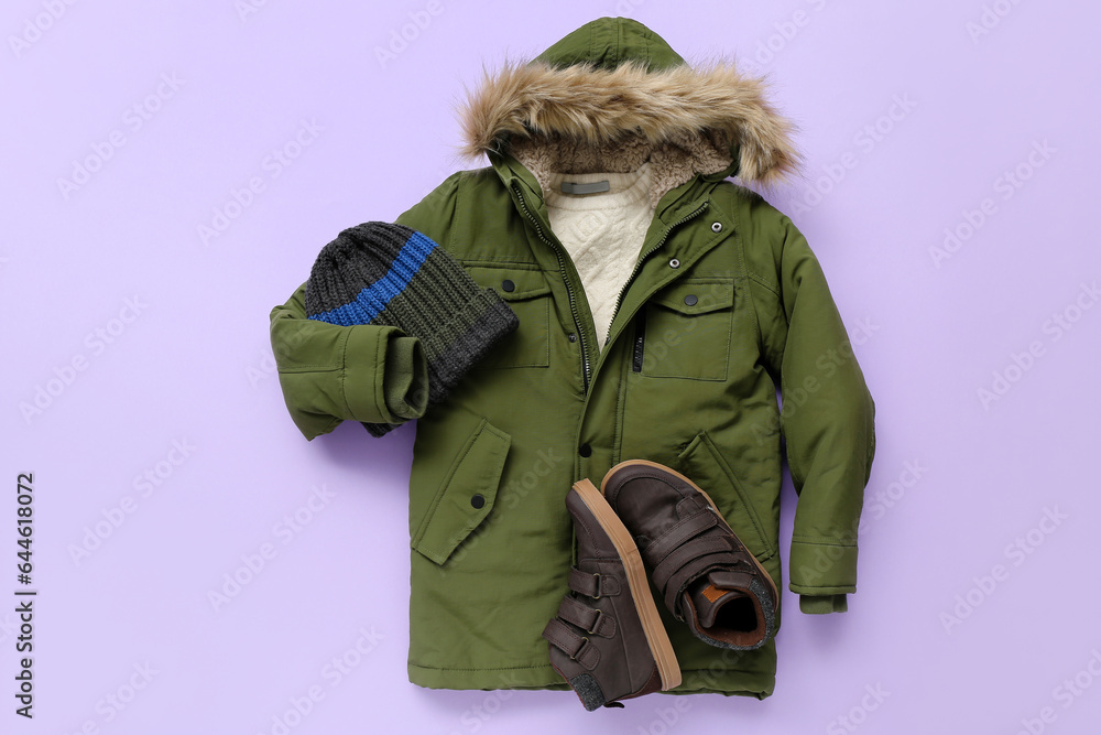 Childrens winter jacket, hat and shoes on lilac background