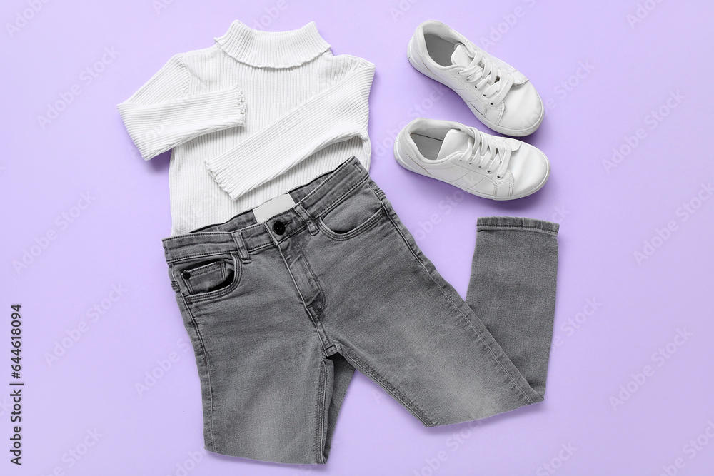 Stylish childrens sweater jeans and shoes on lilac background