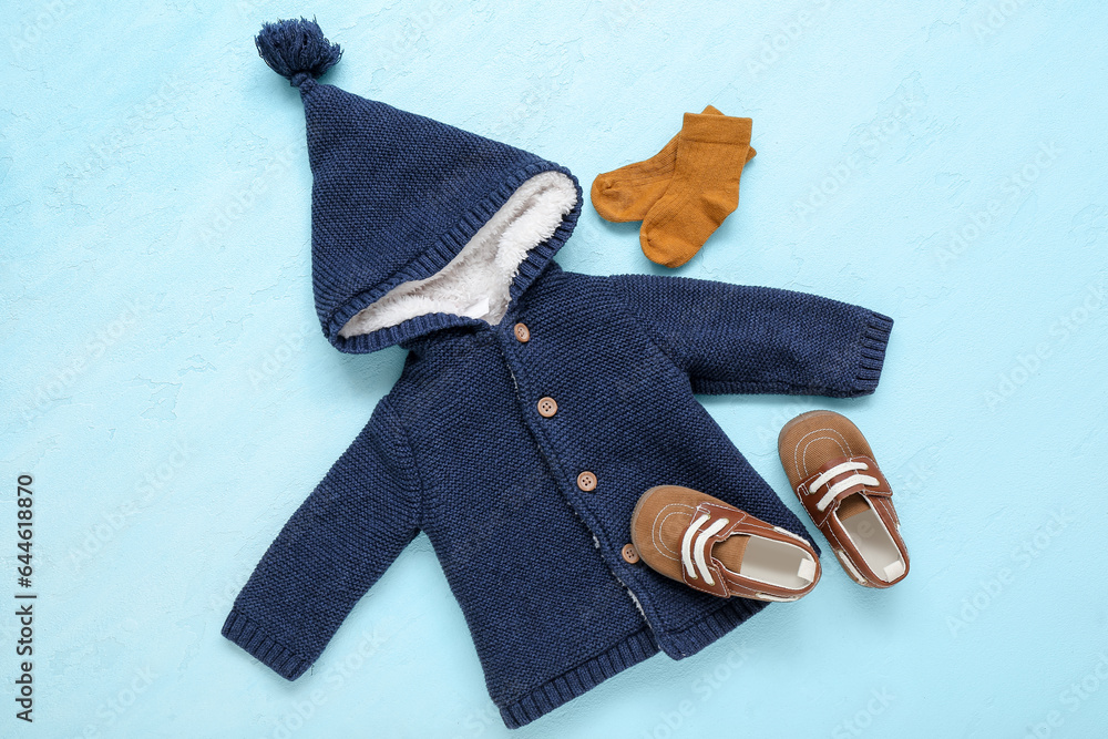 Stylish baby sweater, socks and booties on color background