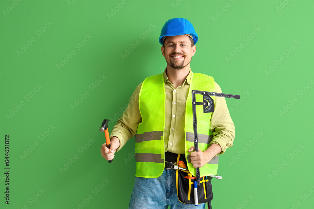 Male builder with tools on green background