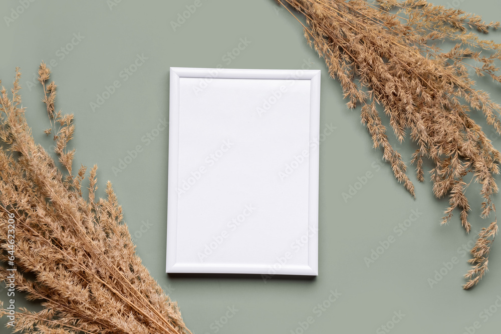 Blank picture frame with pampas grass on green background