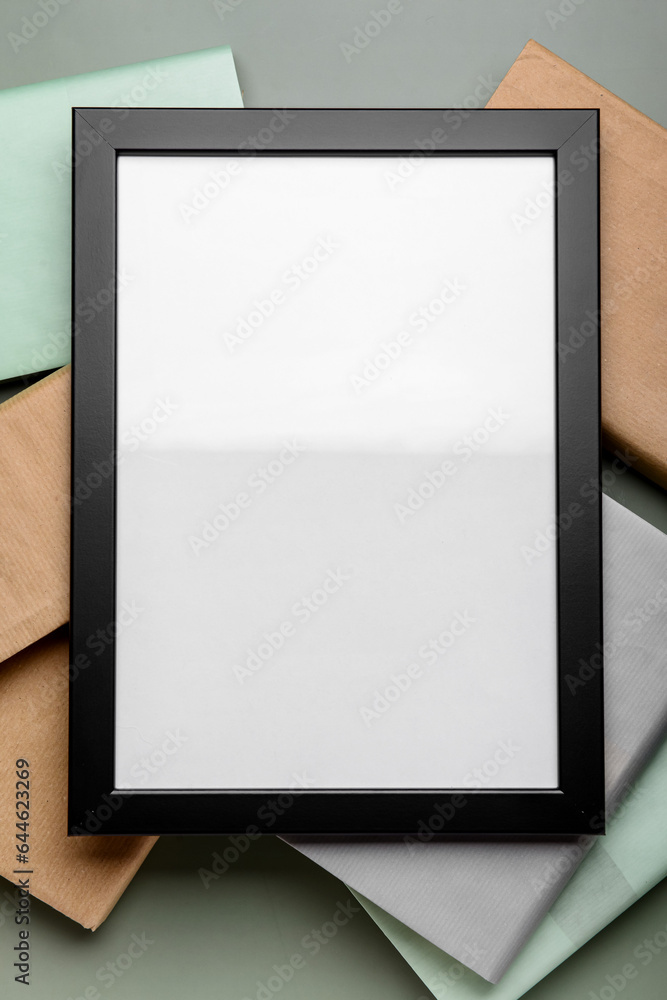 Blank picture frame with books on green background