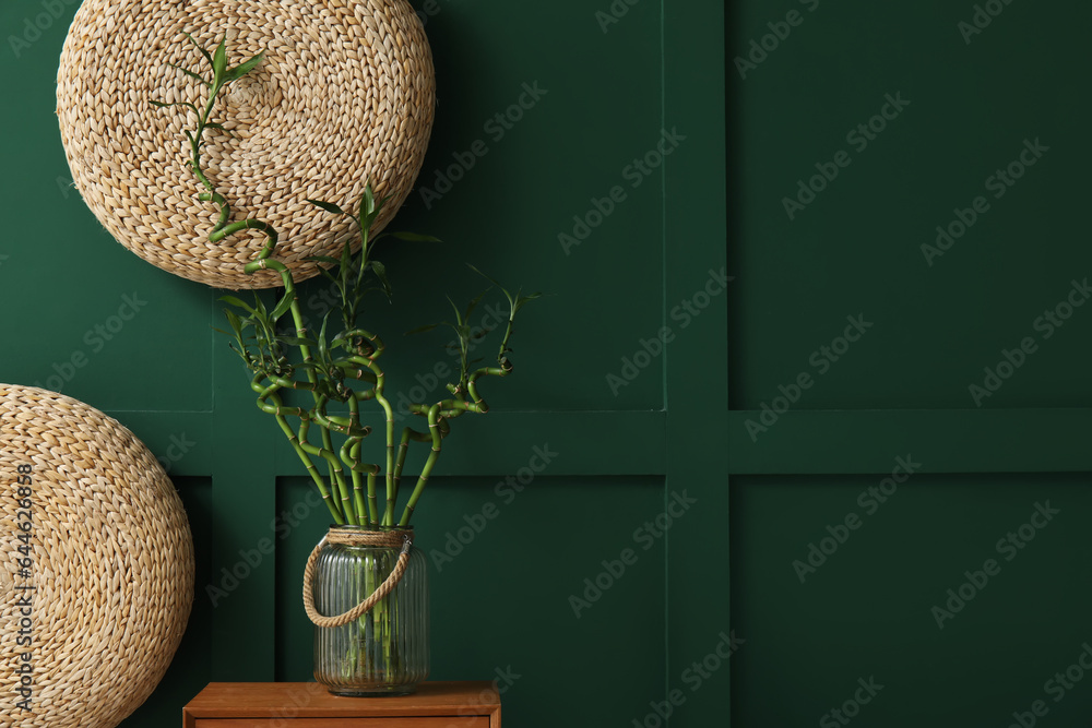 Vase with bamboo stems on table near color wall