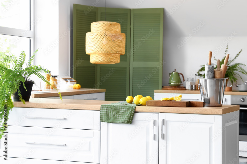 White counters with utensils and lemons in modern kitchen