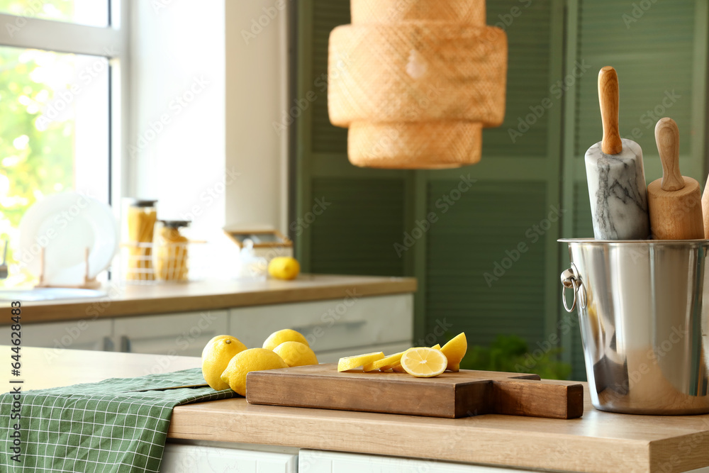 Wooden board with fresh lemons and rolling pins on wooden countertop in modern kitchen